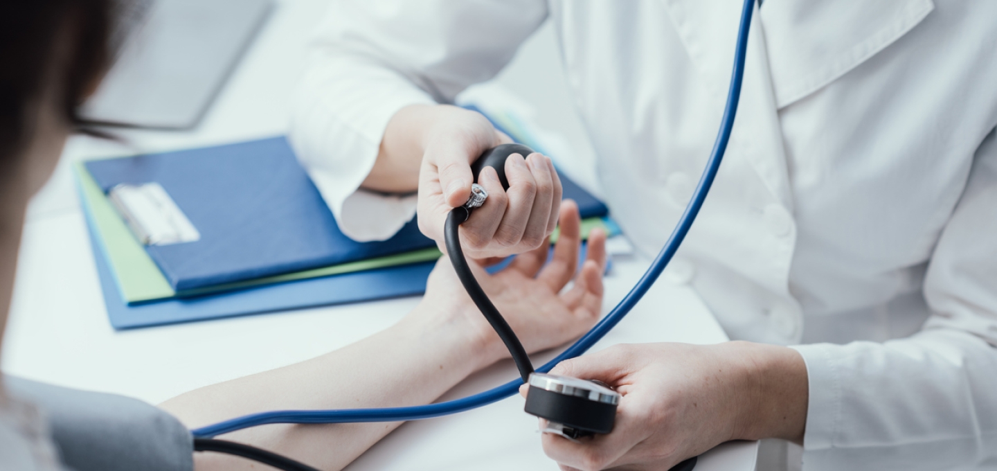 Doctor taking blood pressure in office