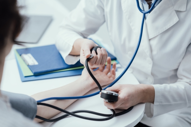 Doctor taking blood pressure in office