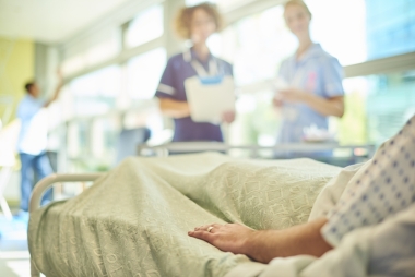 Patient in hospital bed talking to nurses