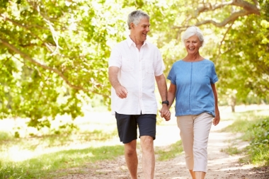 Older man and woman walking in park