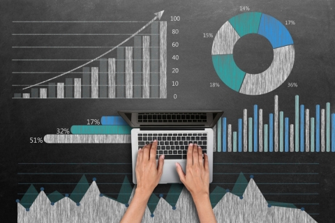 Person working on laptop surrounded by different types of graphs and charts