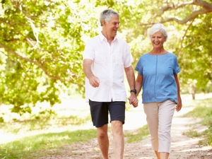 Older man and woman walking in park