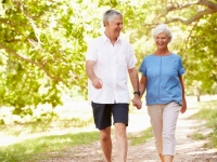 Older man and woman walking in park